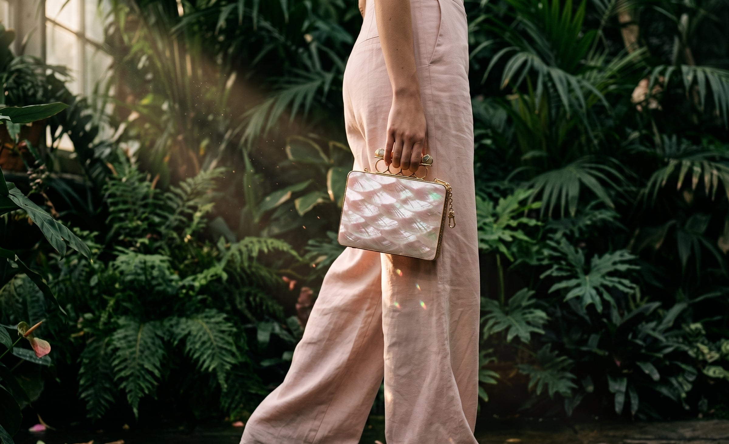 Person holding a patterned handbag in a lush, green outdoor setting