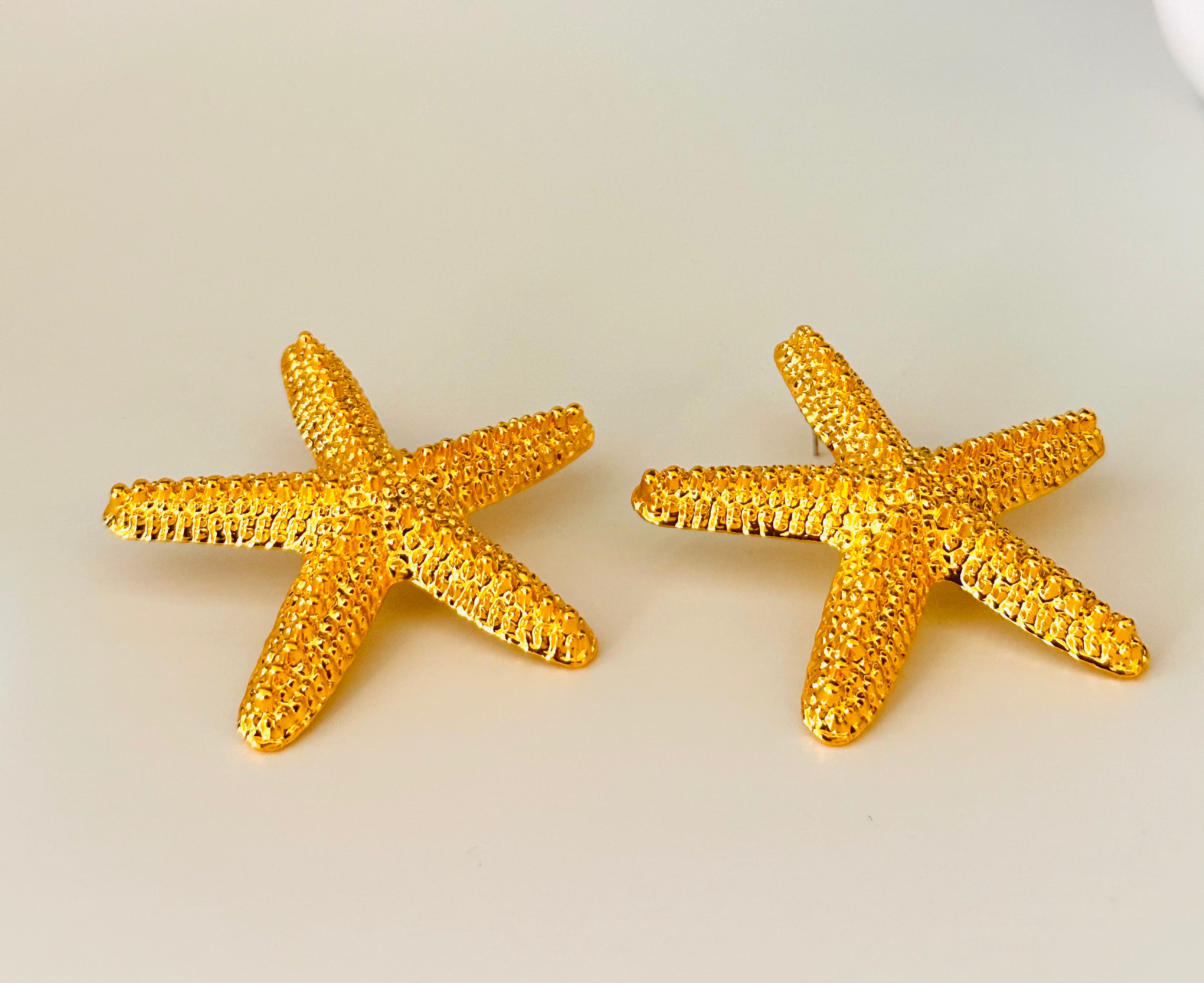 Starfish-shaped earrings with textured gold-plated finish and ocean-inspired design