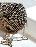 Silver metallic clutch purse with textured surface and detachable chain strap