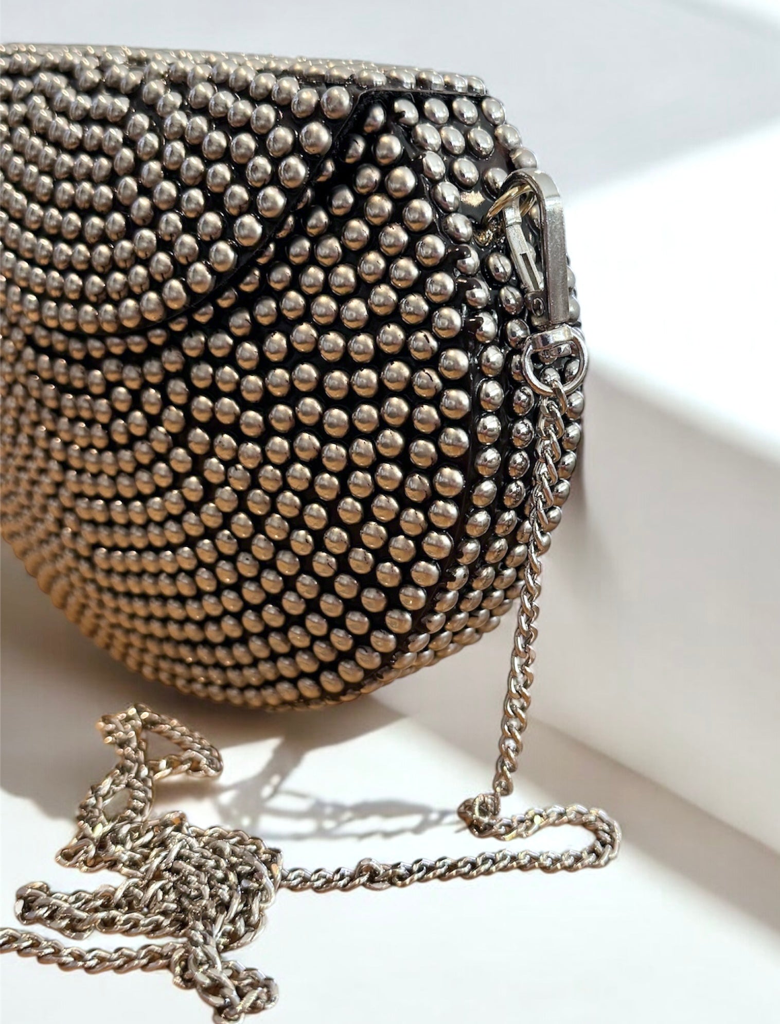 Silver metallic clutch purse with textured surface and detachable chain strap