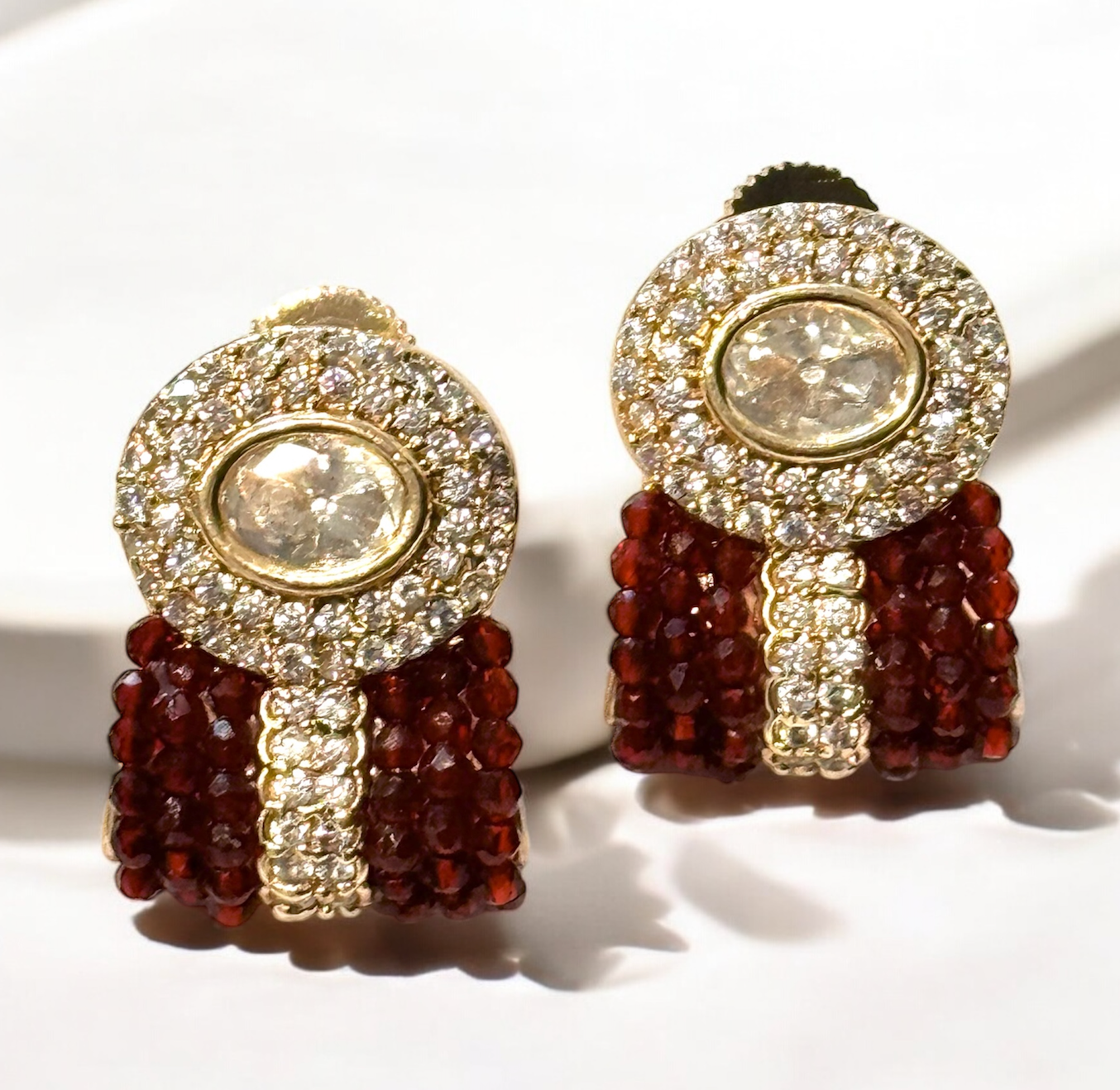 Ruby red stud earrings with faceted stone and gold-plated prong setting